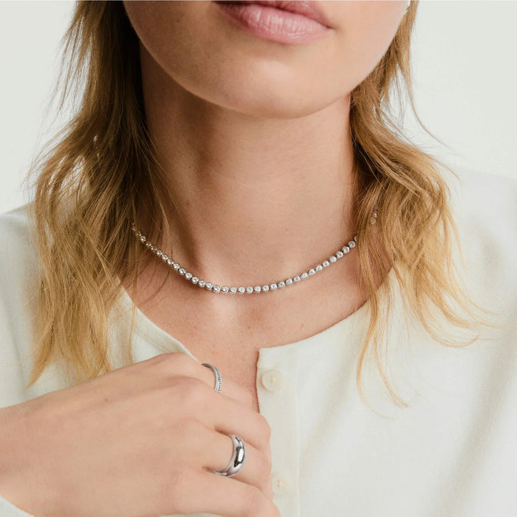 Silver-tone necklace and rings styled with a cream cardigan
